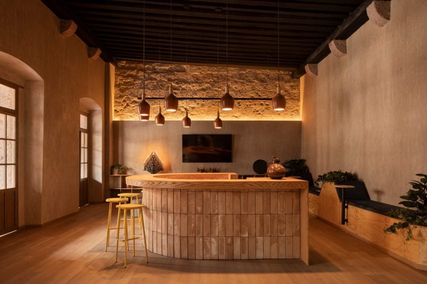 Room with a central horseshoe-shaped coffee bar wrapped in clay tiles