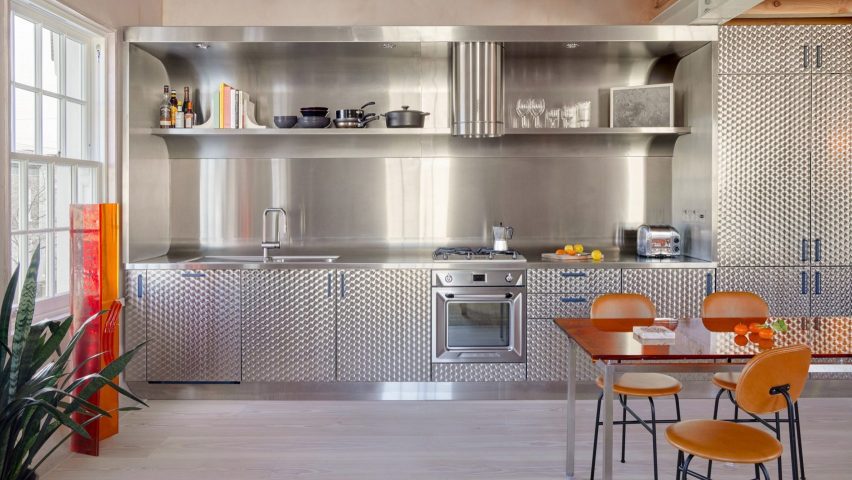 Brushed stainless steel kitchen with orange chairs