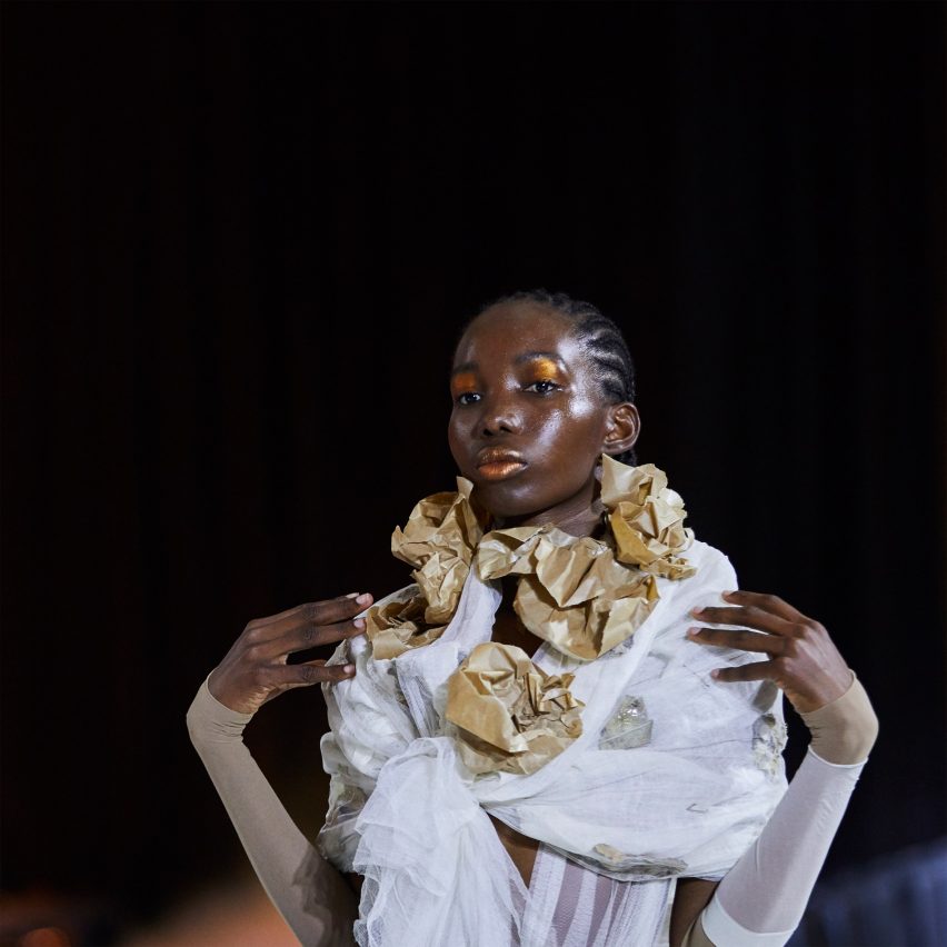 a fashion student wearing a garment in tones of gold and white