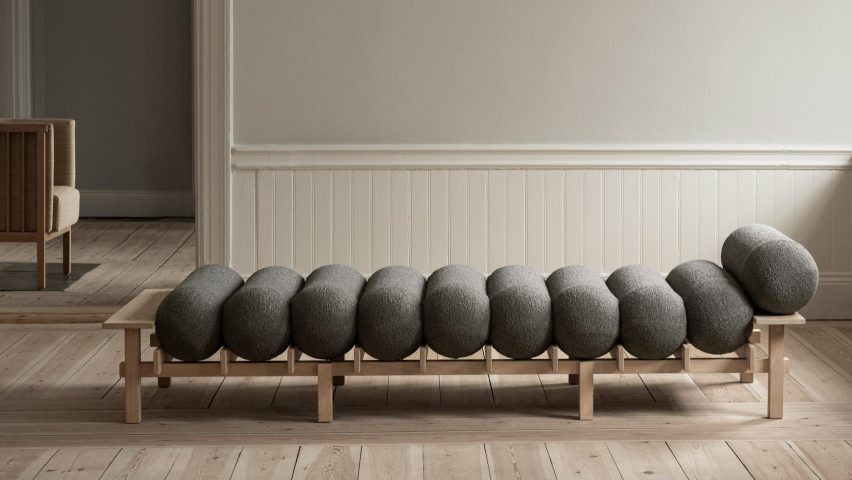 Grey cylinder cushions on wooden framed daybed