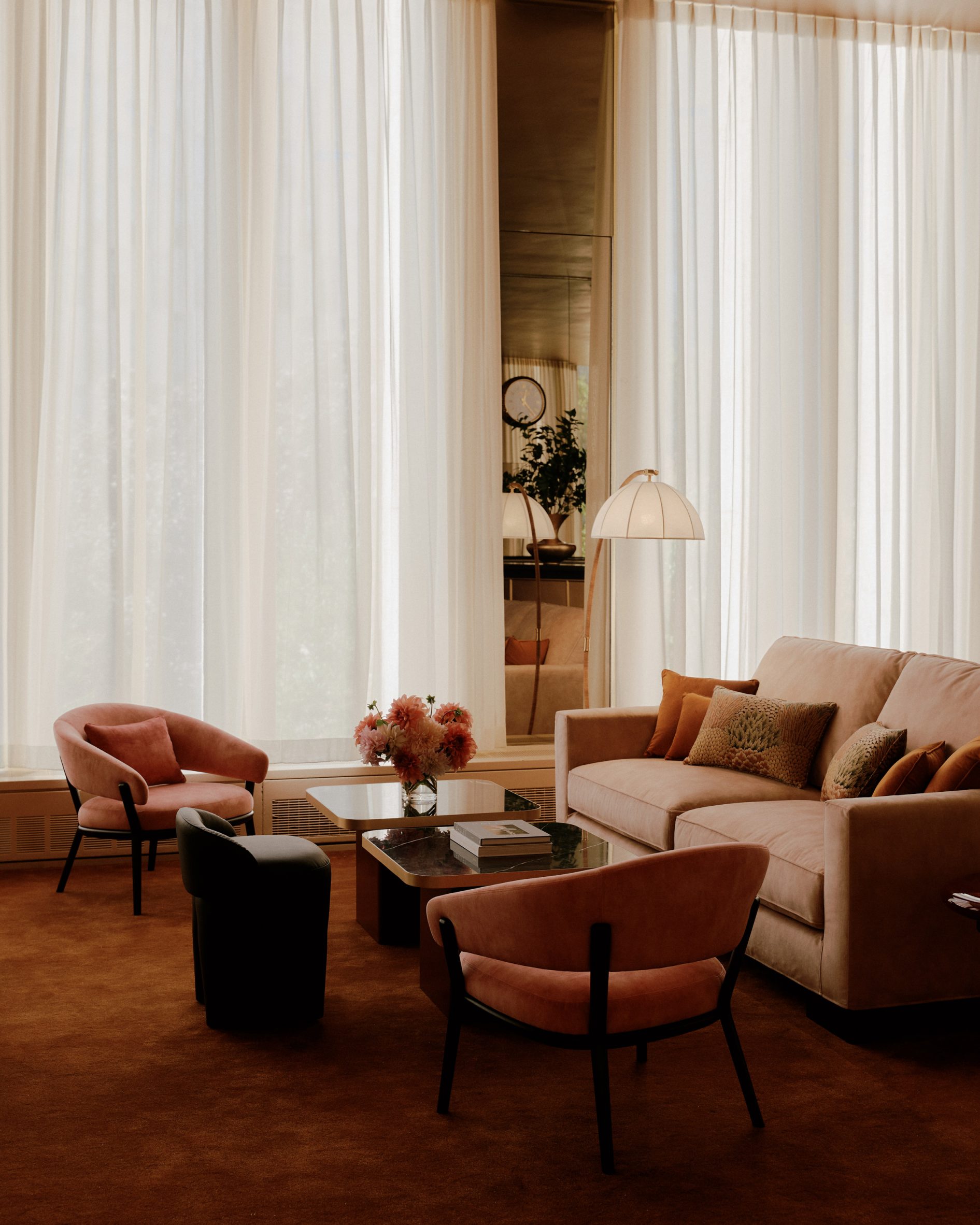 A lounge area on rust carpet and against sheer curtains