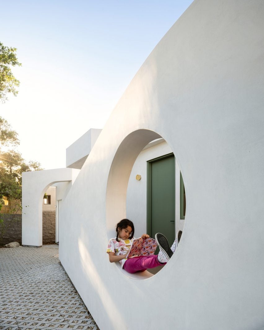 Girl reading within a circular hole in a white wall