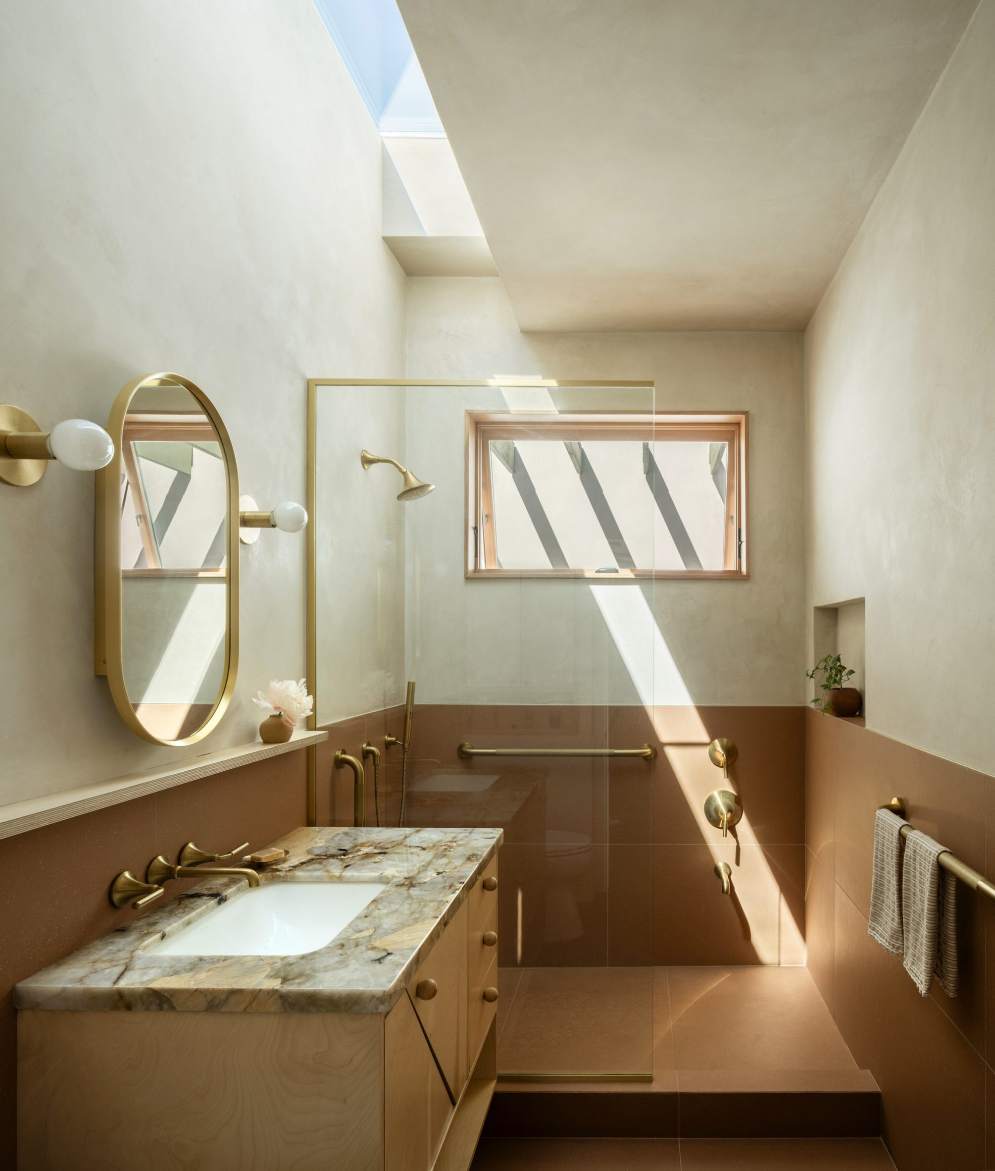 Bathroom with dark tiles on the lower walls, and a skylight above