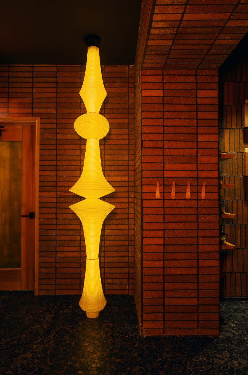 Tall Noguchi paper lantern against straight-stack tiled wall