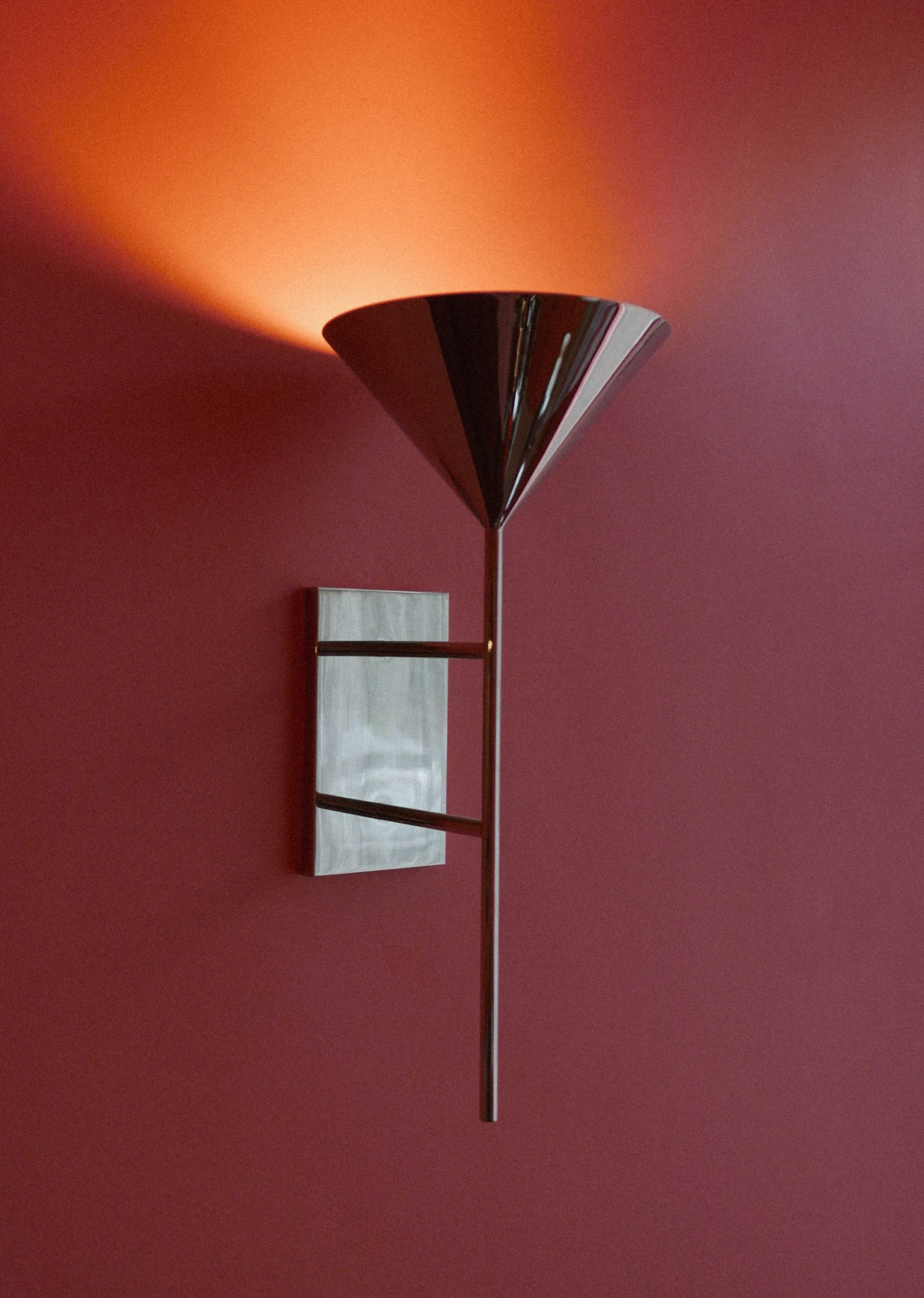 Nickel-plated sconce mounted on a pink wall