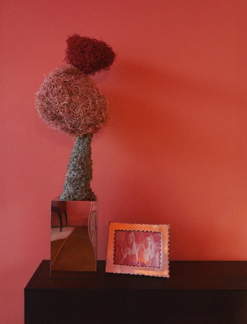 A sculpture and a framed photograph against a pink wall