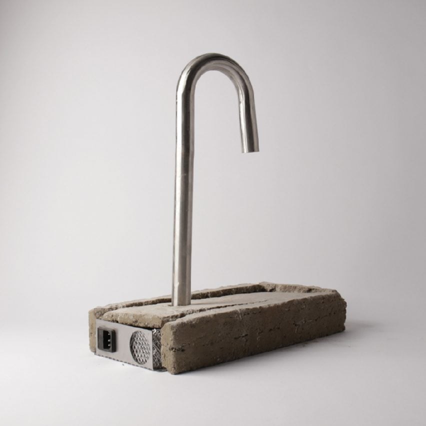 A photograph of a silver metal tap atop a rectangular block of grey concrete, against a white backdrop.