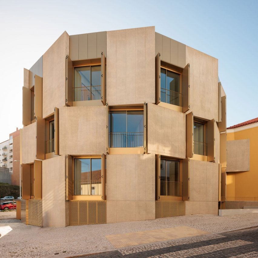 Gold aluminium shutters create "defensive" facade for Portuguese housing block