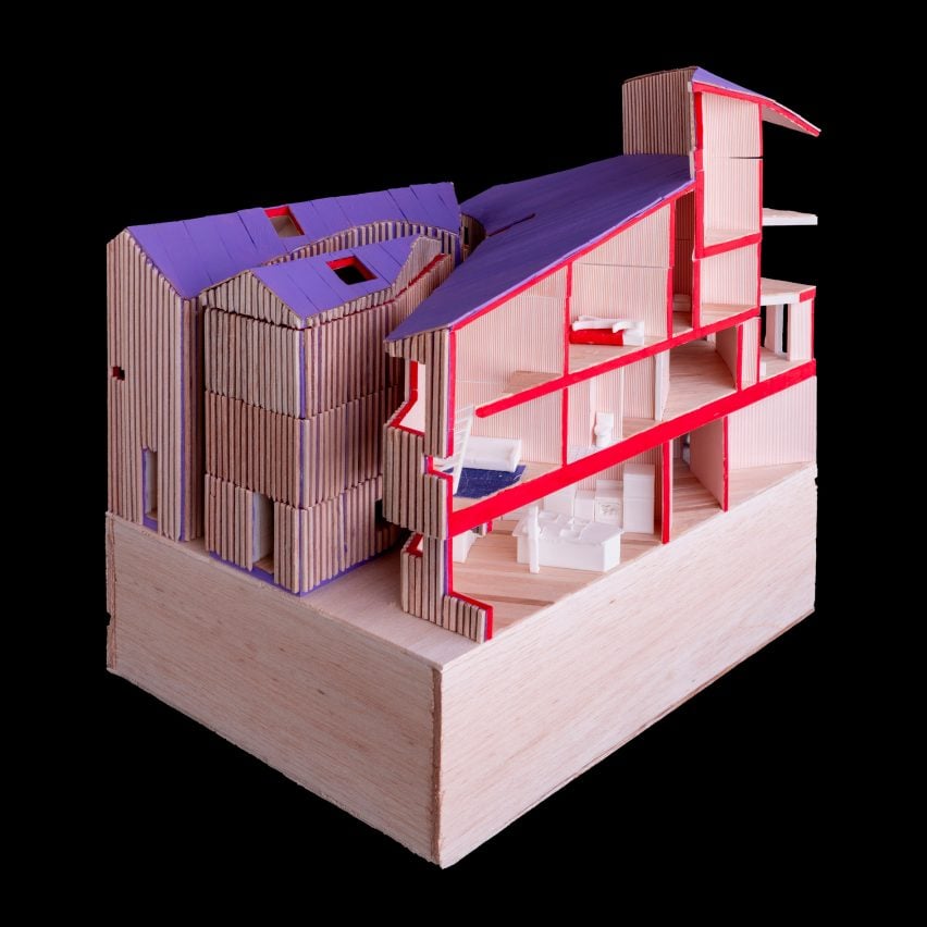 A photograph of a wooden architectural model in tones of beige, red and purple.