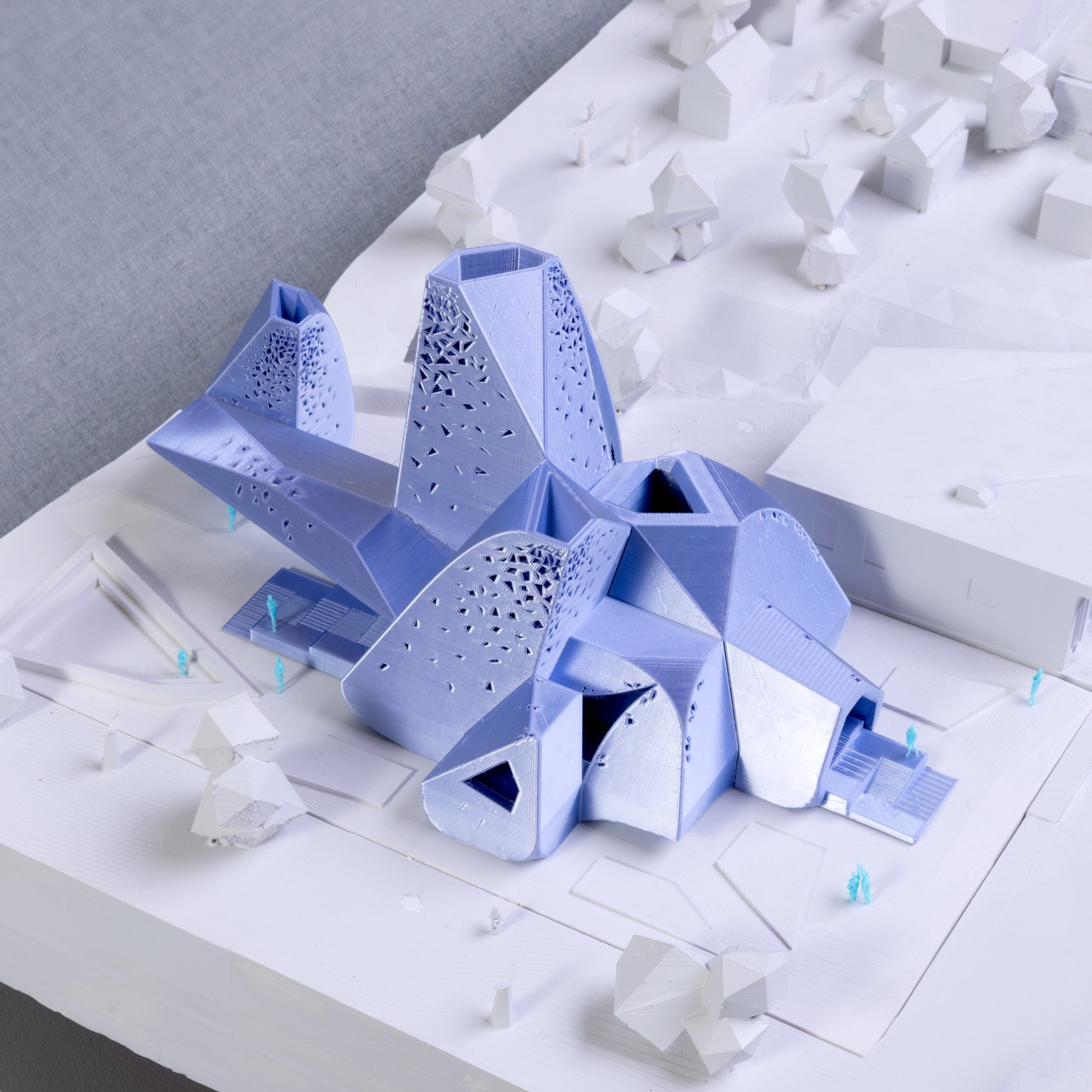 A photograph of an architectural model of a chapel in tones of blue atop a white surface.