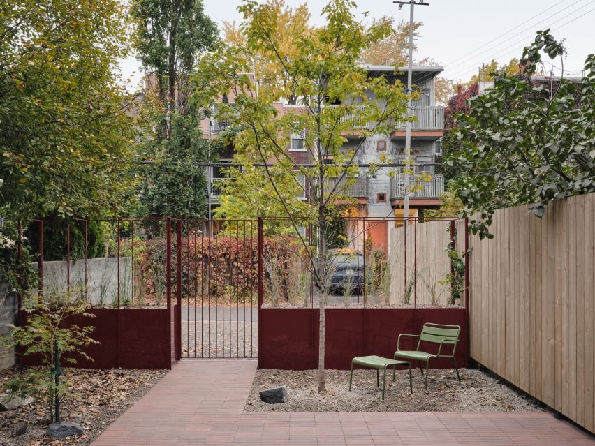 Patio separated from a street by a metal structure that incorporates raised planters and a gate