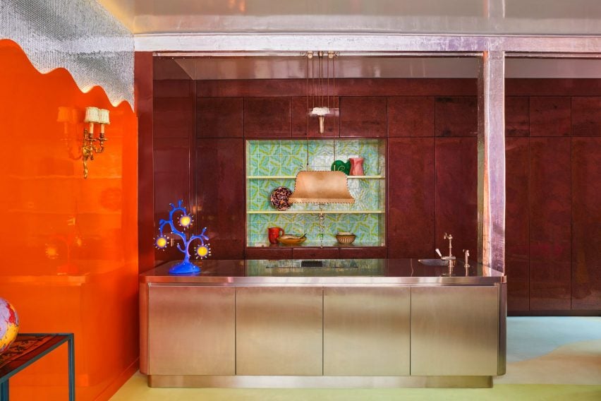 Metal kitchen island flanked by orange walls