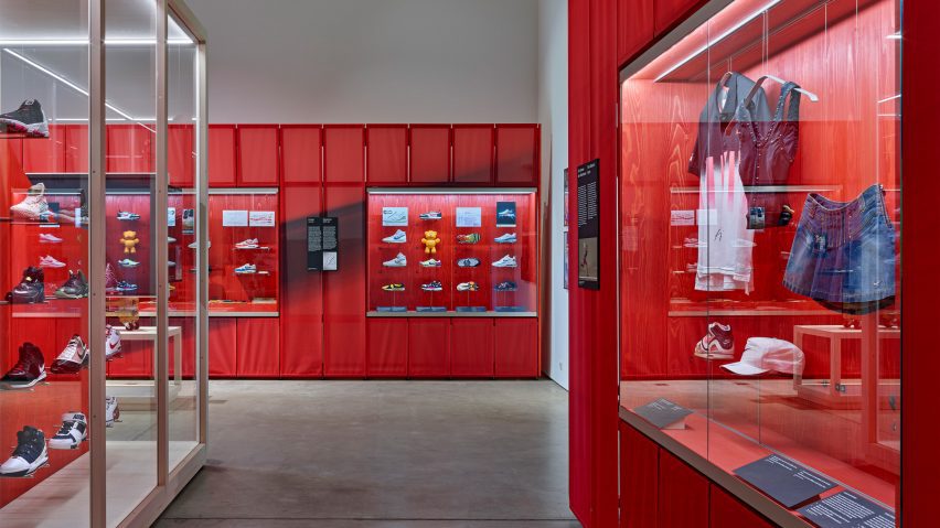 A photograph of an exhibition displaying shoes and apparel against red backdrops.