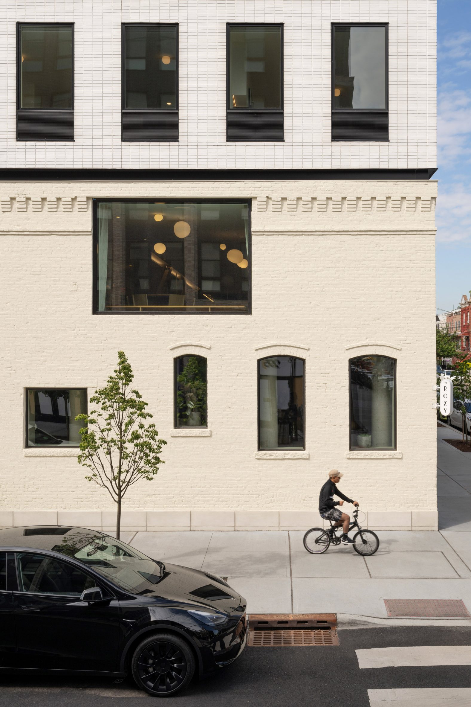 Corner of a building with a beige brick beige and a white addition above