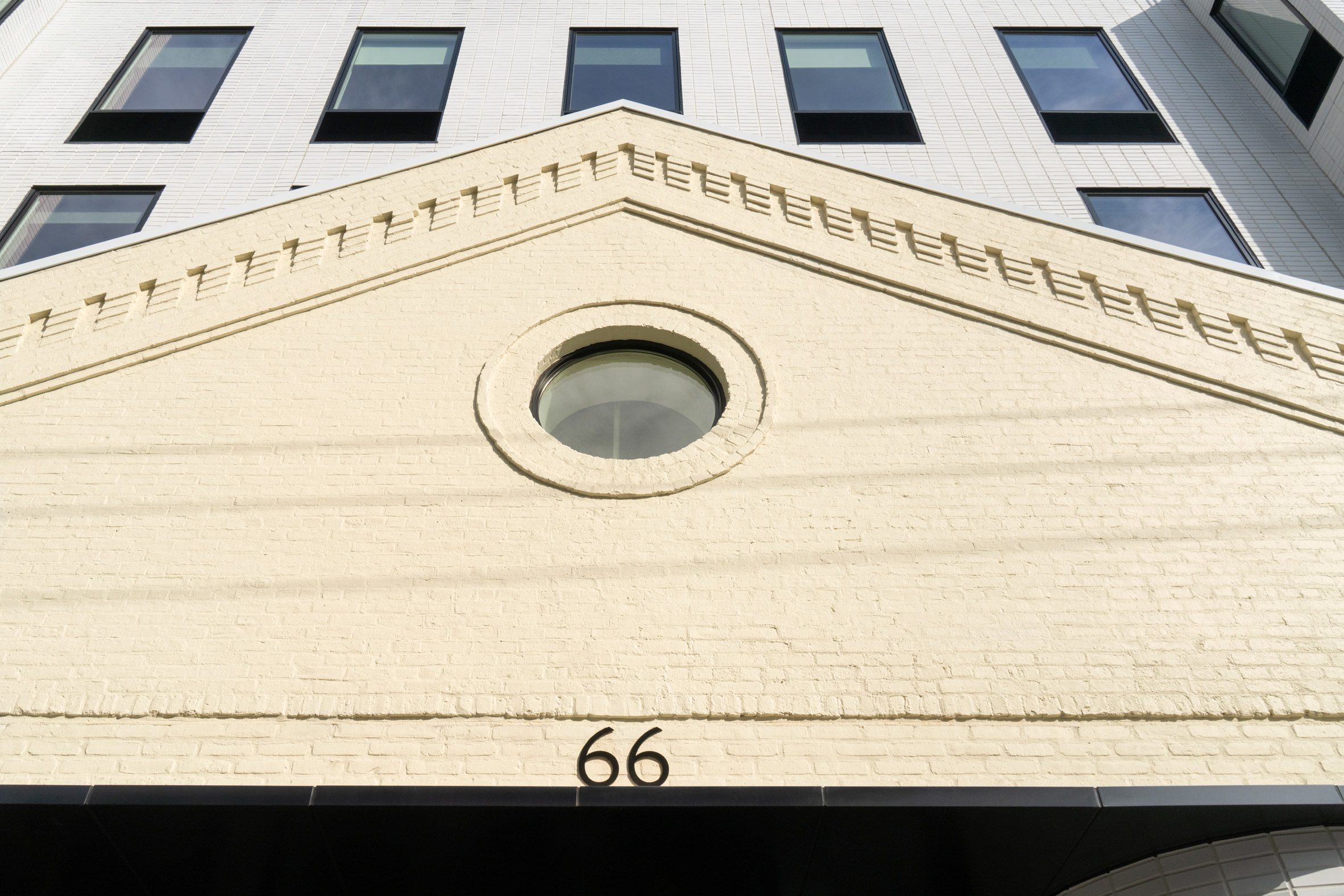 A gabled roof detail of an old warehouse building, with new construction behind