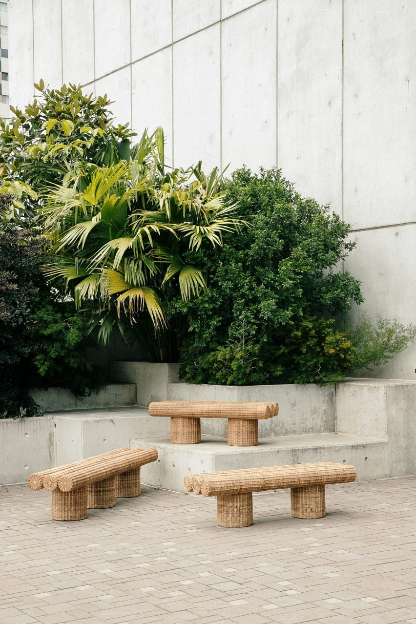 Photograph of three benches that have been woven from yaré. The benches are placed in an urban setting with greenery in the background.