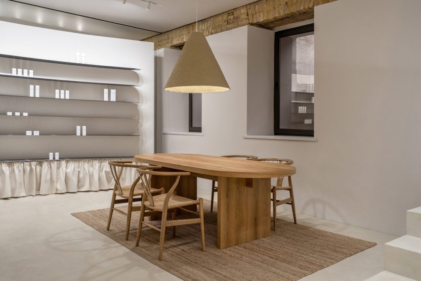 Photograph of the client meeting area in the showroom interior. Large wooden table with a paper mache pendant light.