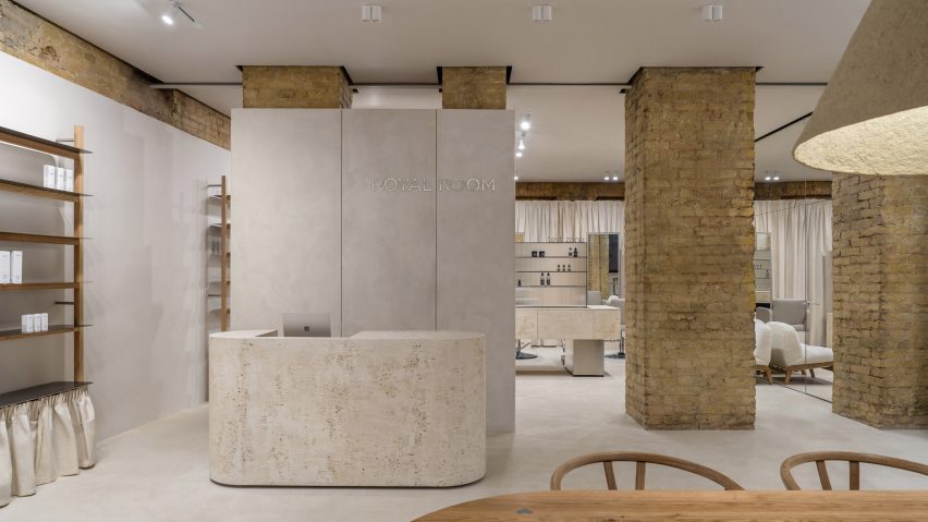 Photograph of a minimalist, open plan showroom with a large reception desk and pillars made from exposed yellow brick.