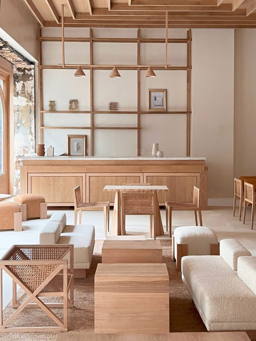 Photograph of a minimalist lounge area with a reception desk. The furnishings are mostly crafted from a light toned wood.