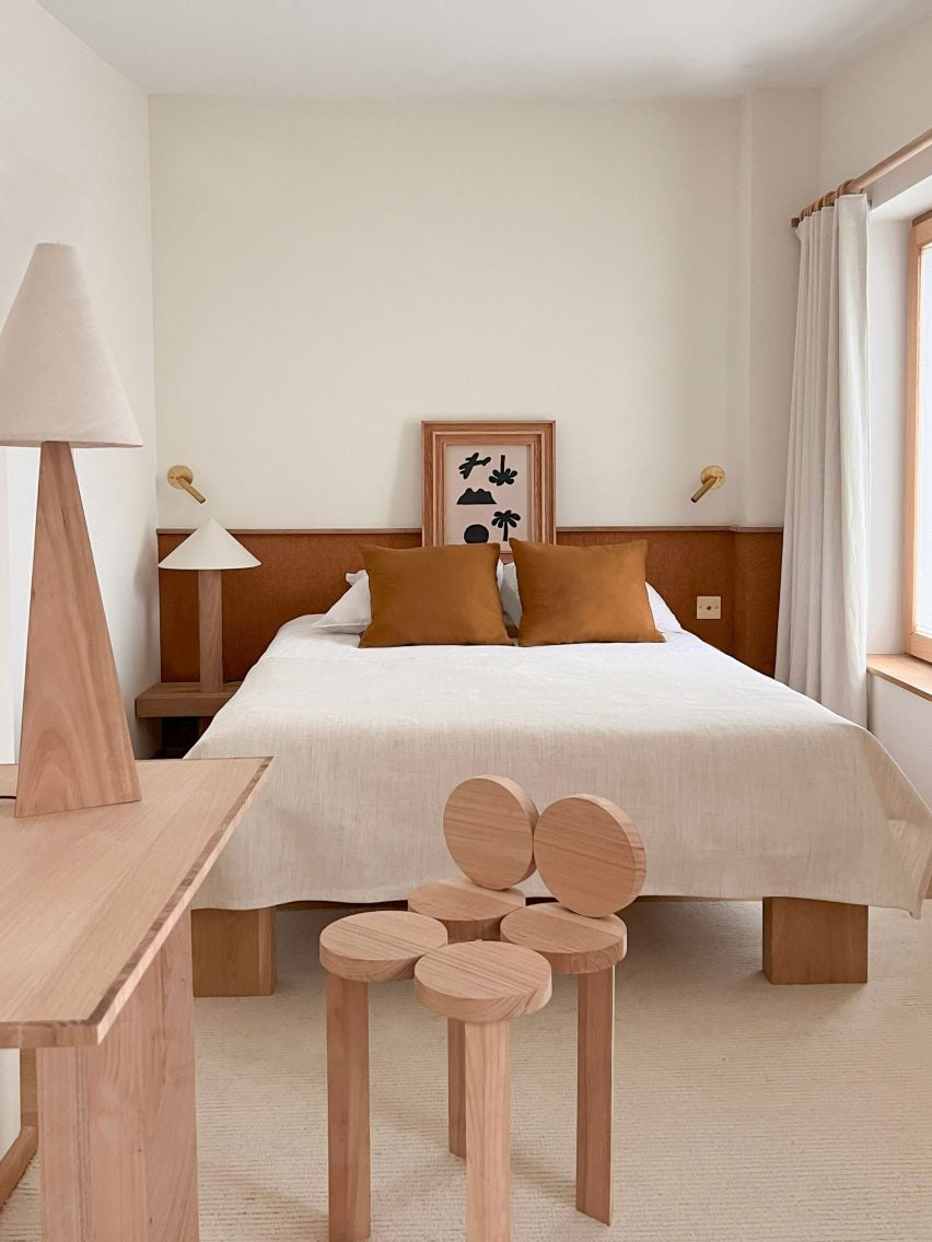 Photograph of a hotel bedroom with a minimalist scheme and wooden furniture.