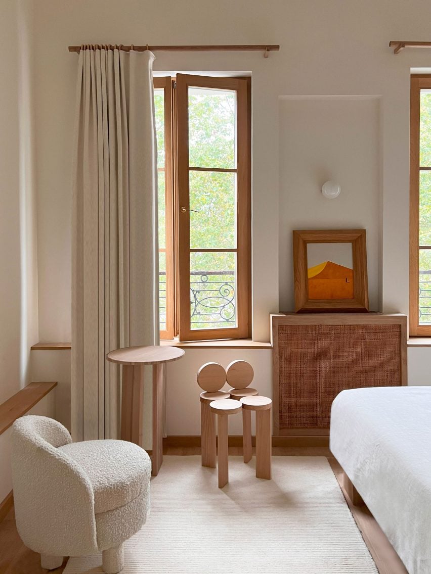 Photograph of a minimalist hotel bedroom with a seating area by a large window.