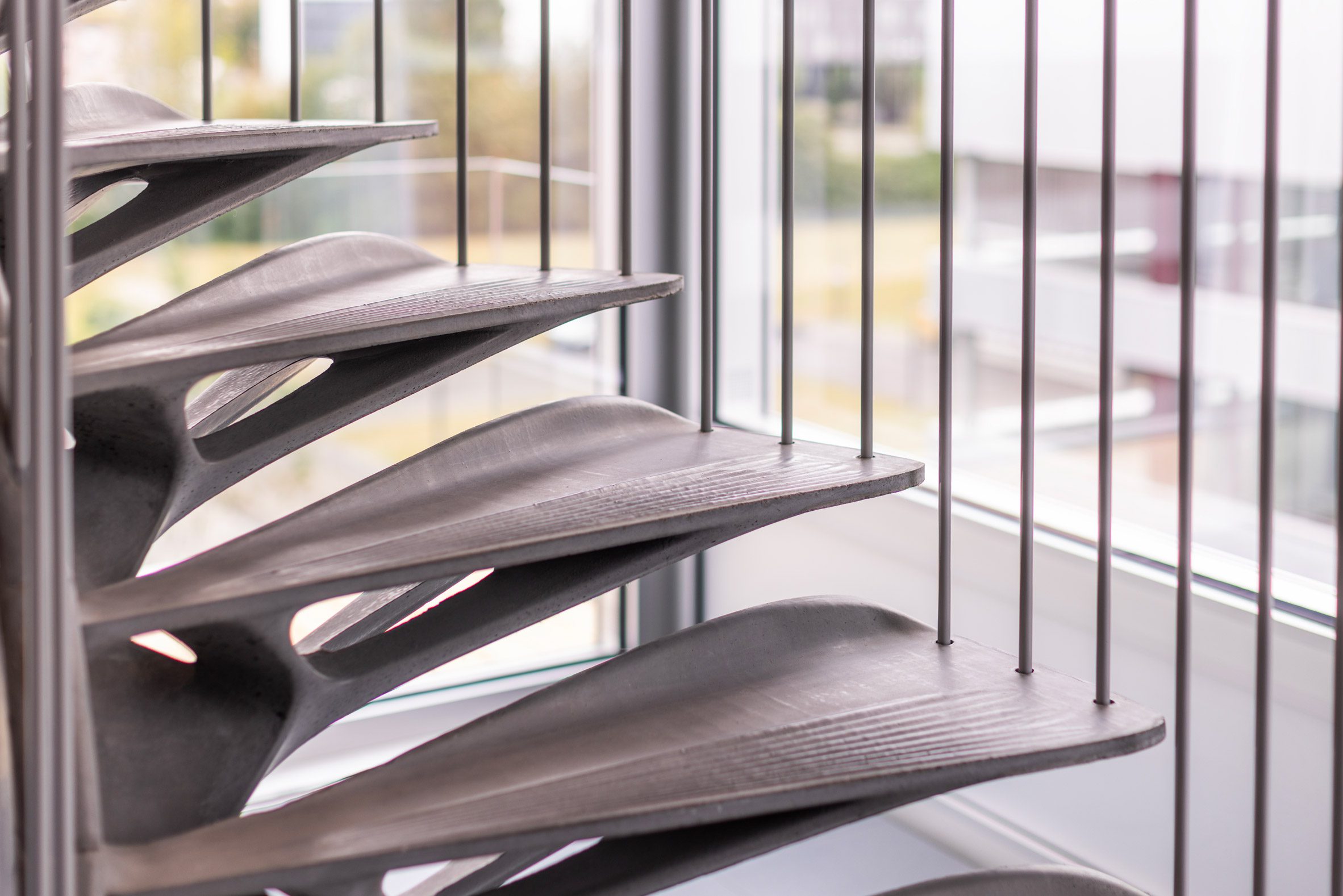 Medium close-up photo of the slender cantilevered concrete steps of a spiralling staircase