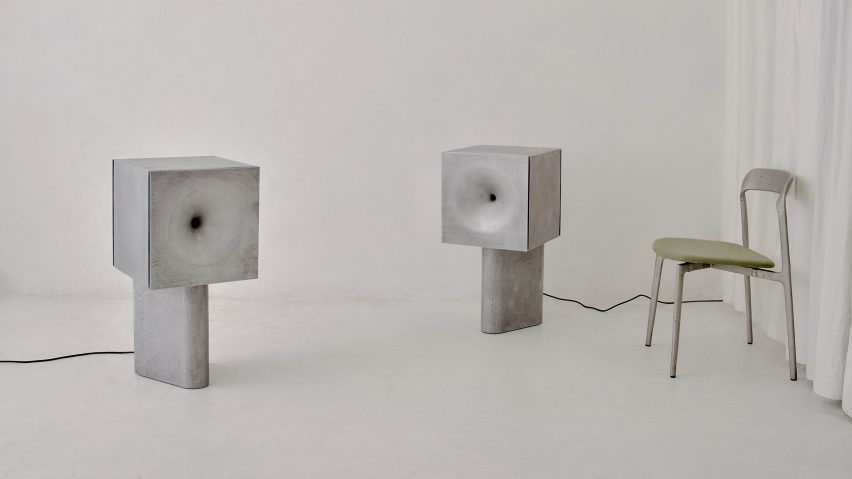 Two cast speakers in a white room with a chair