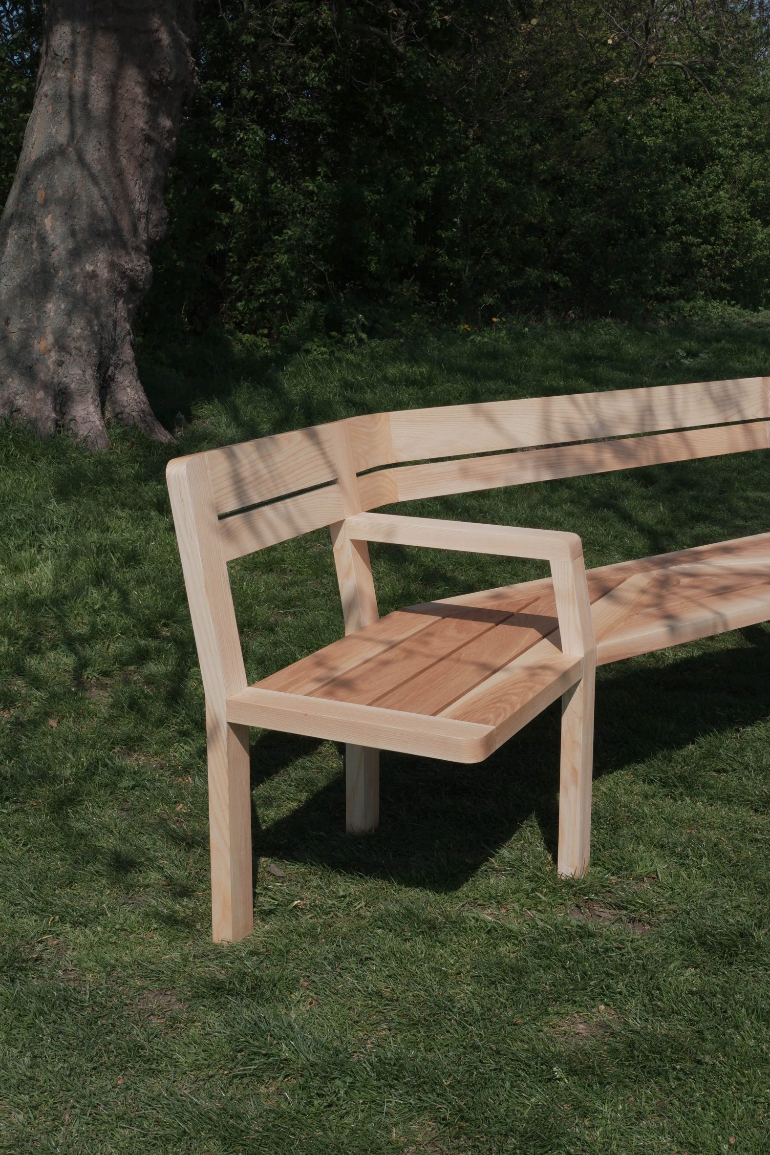 A photograph of a wooden bench within a green outdoor space.