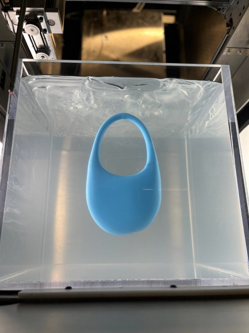 A photograph of a 3D-printed blue bag suspended in clear gel.