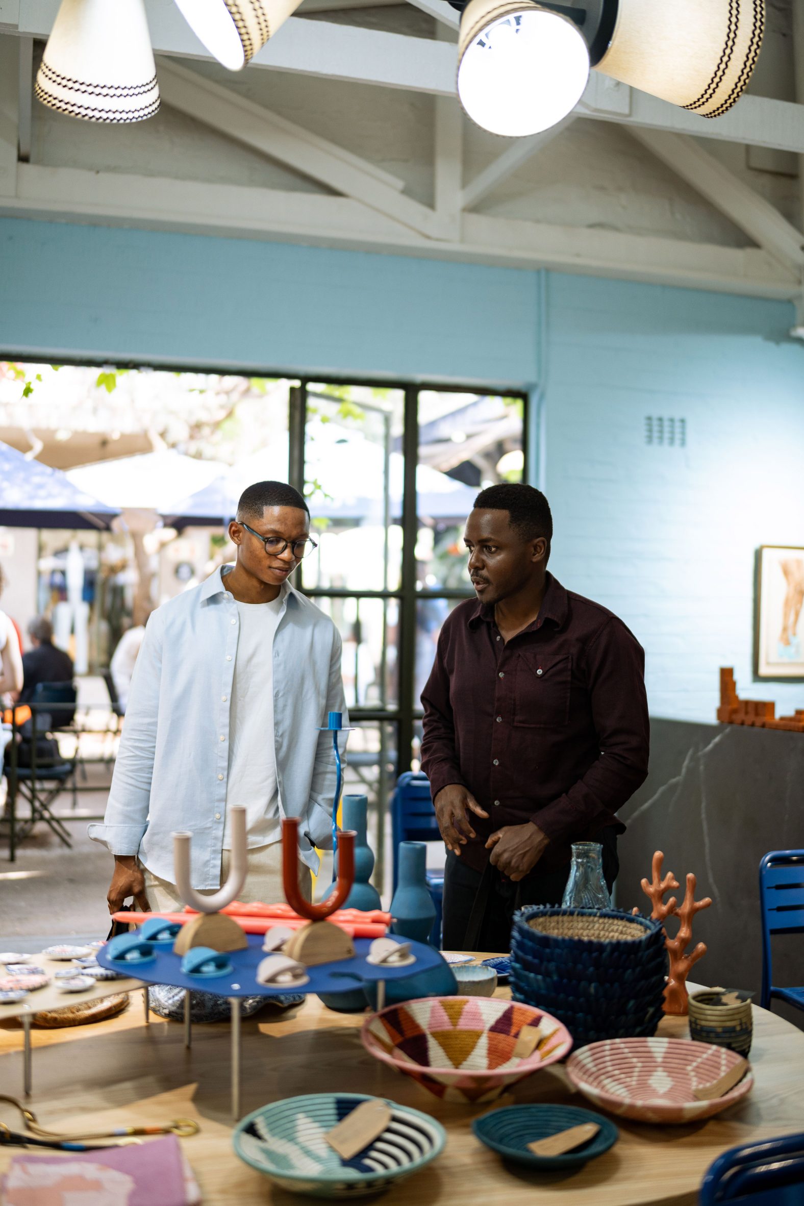 Two men standing next to a display of homeware