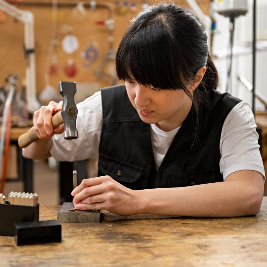 a photograph of a person using a hammer at a desk
