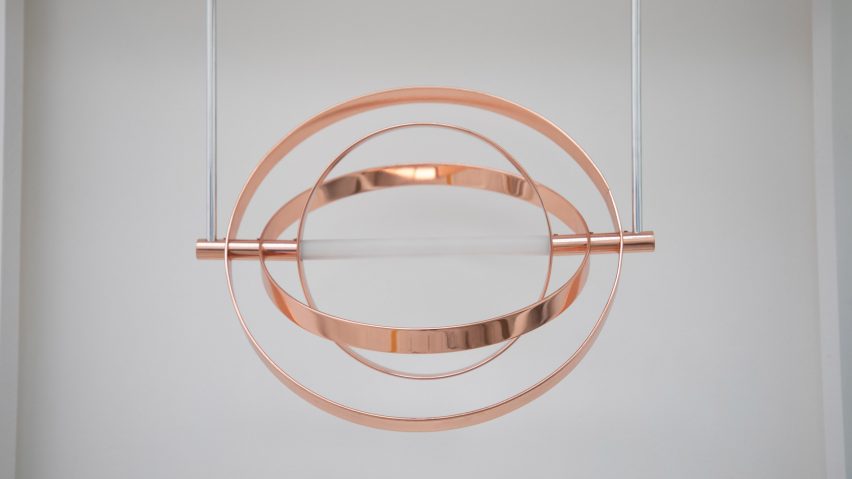 A photograph of a hanging circular metal installation in copper tones.