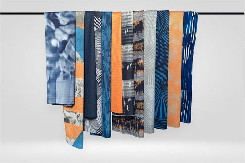 A photograph of a collection of fabrics hanging from a black line, in tones of blue, orange and grey.