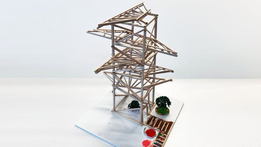 A photograph of an architectural model made from brown wooden sticks, in a geometric shape, against a white backdrop.