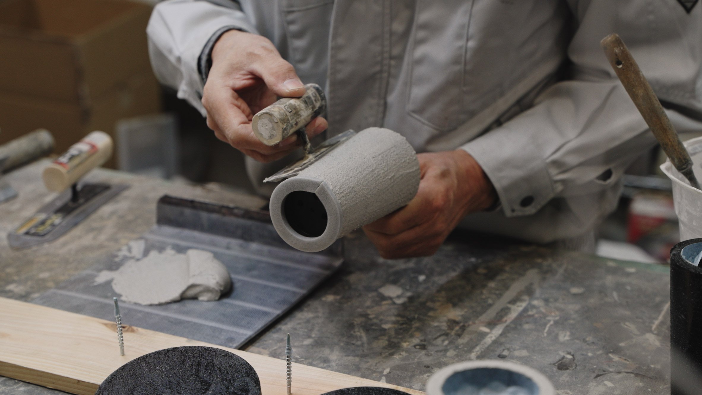 Person smoothing grey material onto exterior of lamp base