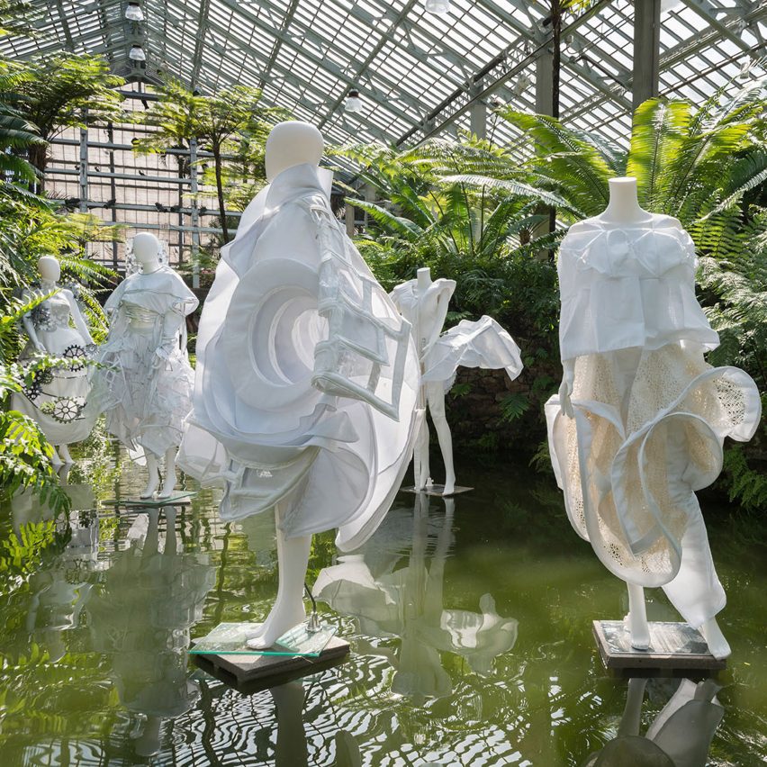 a photograph of people wearing white garments atop a body of water, surrounded by greenery