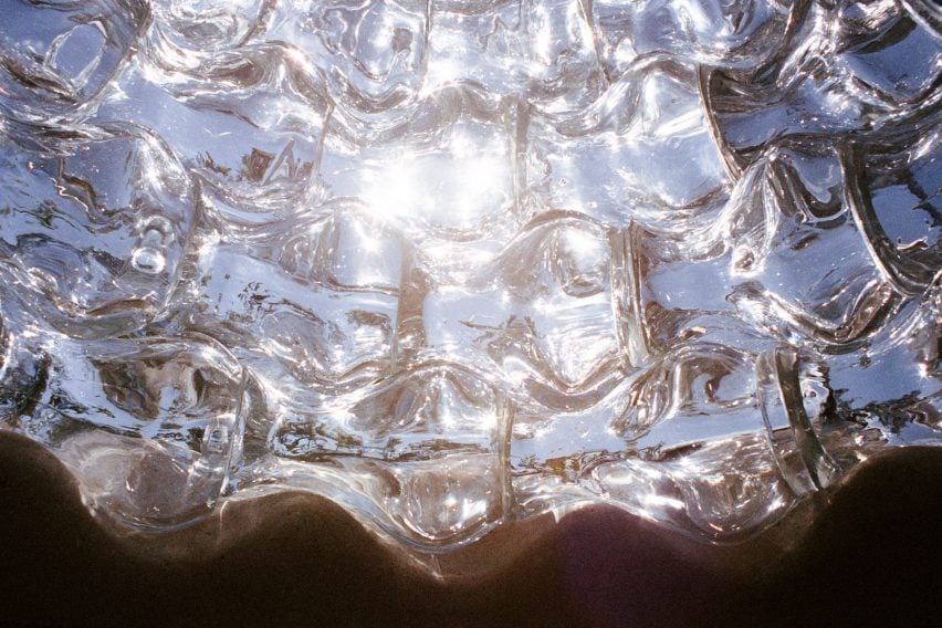 Photo of the inside of the Serpentine Bell sculpture, showing a distorted view of the blue sky seen through wavy glass blocks