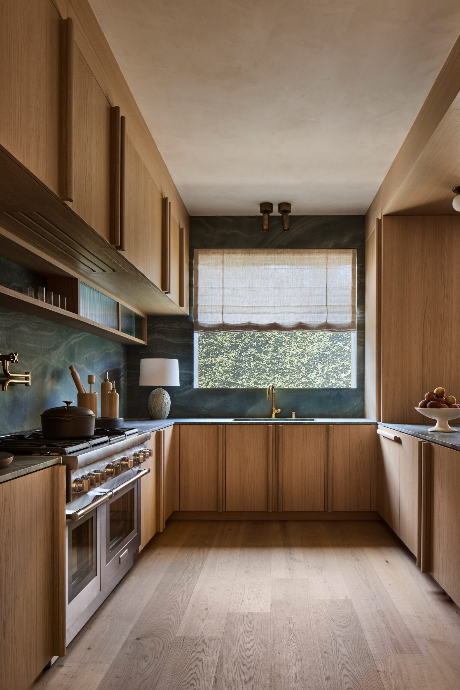 Oak millwork surrounds blue-green stone counters and backsplash