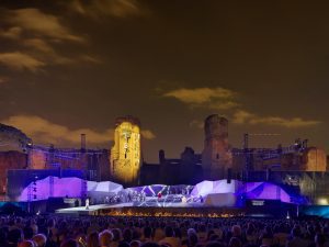 Photo of Studio Fuksas's set for Tosca and Turandot at night with purple and white projections covering the whole stage