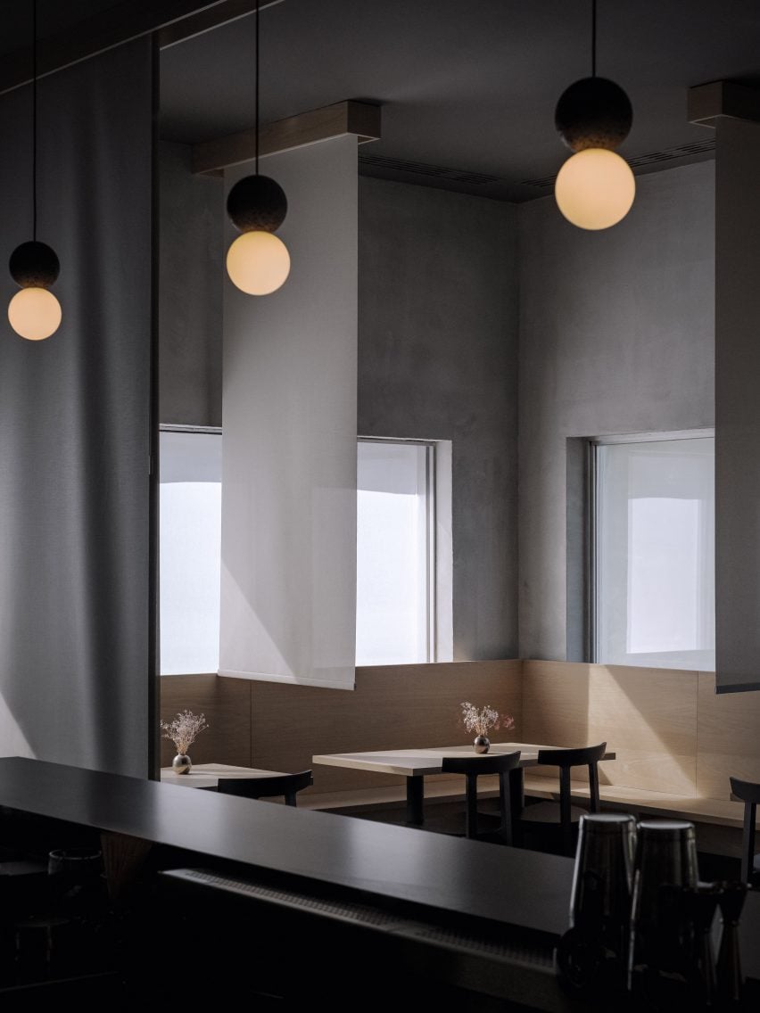 Tables arranged along a white oak bench and divided by vertical sheets of fabric