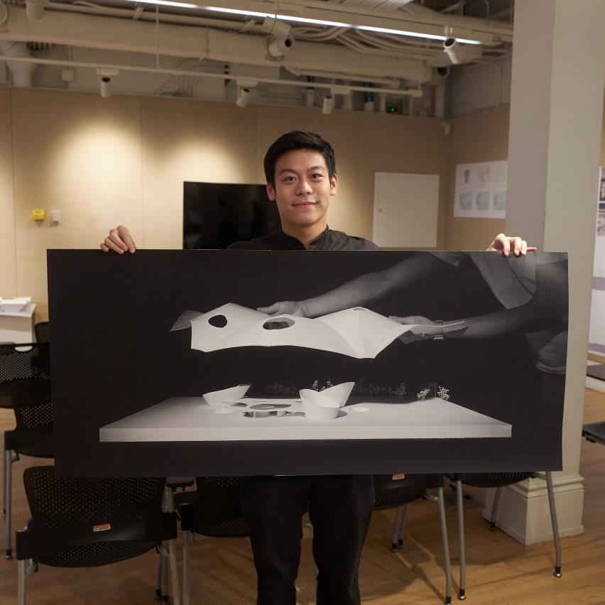 Photograph of a student holding a large poster displaying their work.