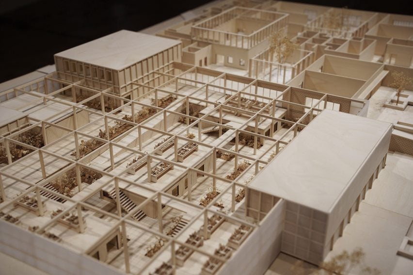 A cropped photograph of a wooden architectural model of a building in rectangular structures.