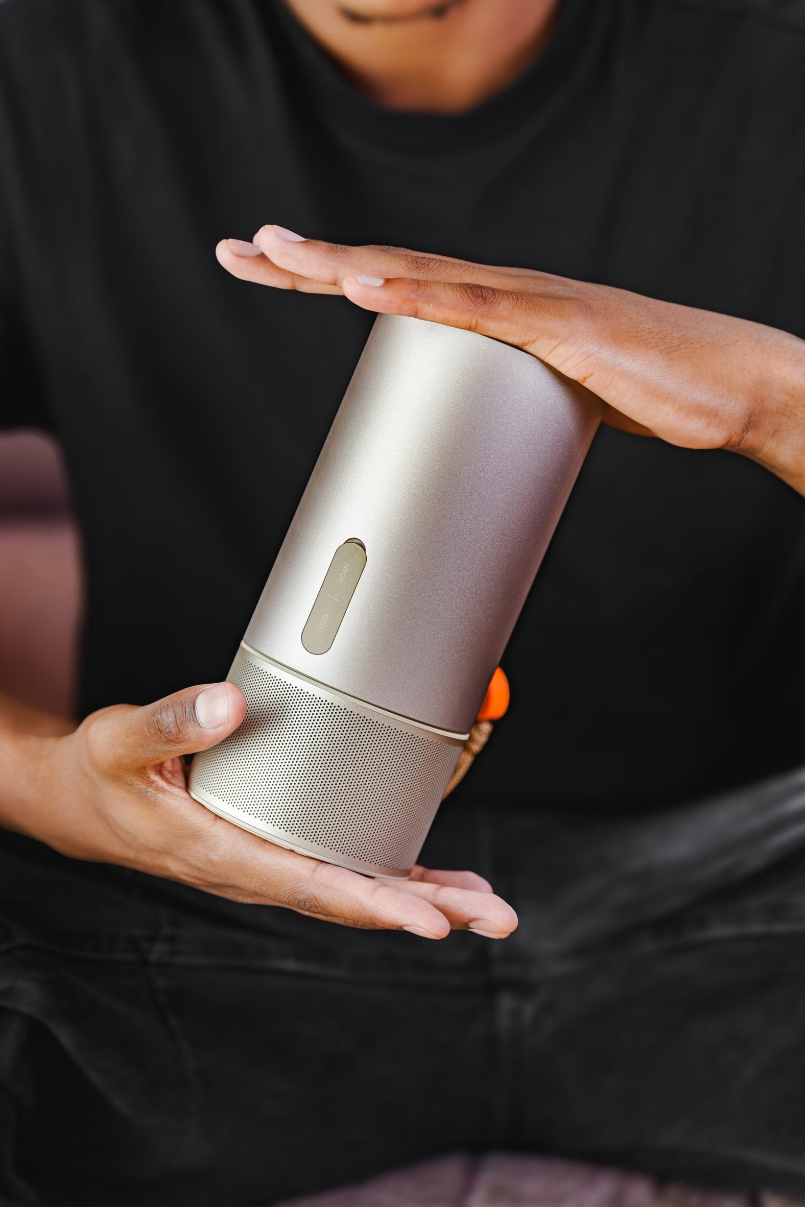 Cylindrical design speaker held between two hands