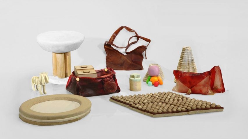 A photograph of a selection of design objects including bags and a stool, in various tones of beige, red, orange and white, all photographed against a grey backdrop.