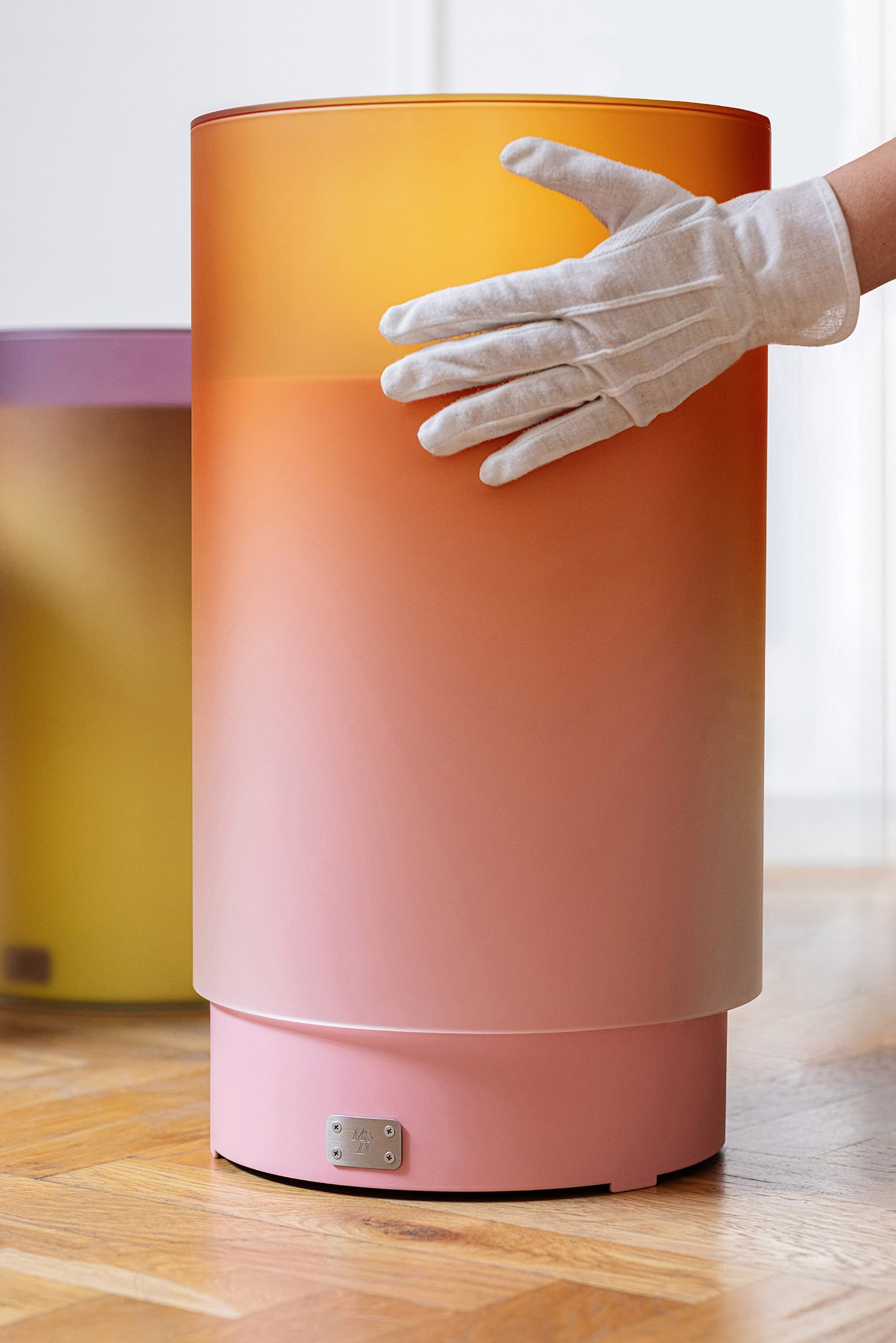 Hands lifting a glass cylinder off a metal table