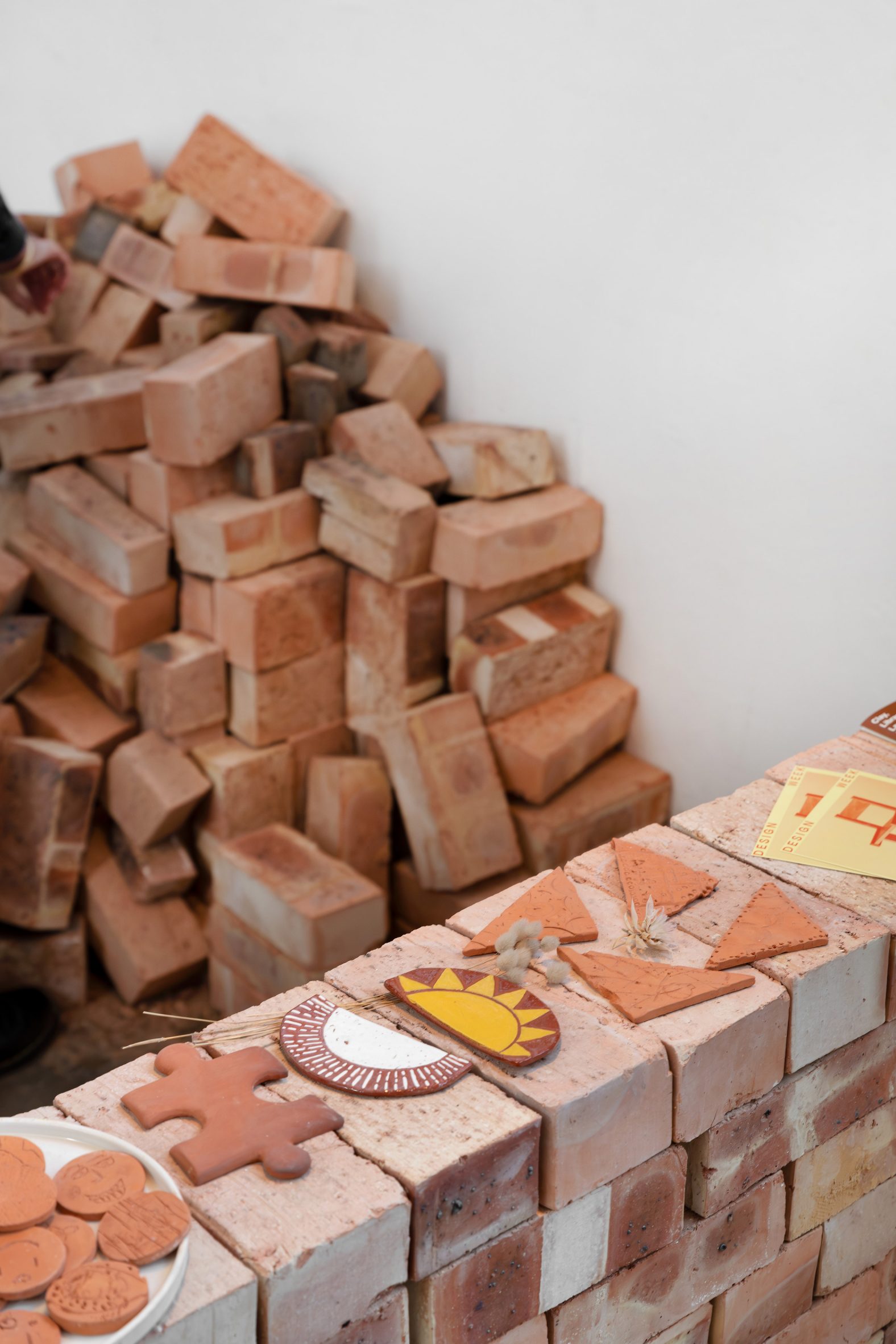 Photo of small handcrafted and patterned tiles on display on a low brick wall