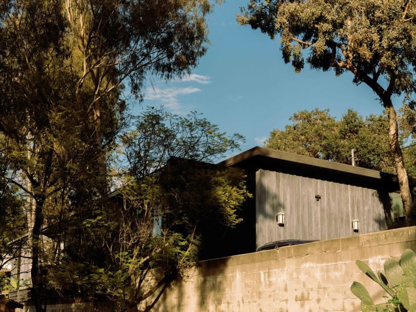 Exterior of house with weathered timber cladding and surrounded by trees