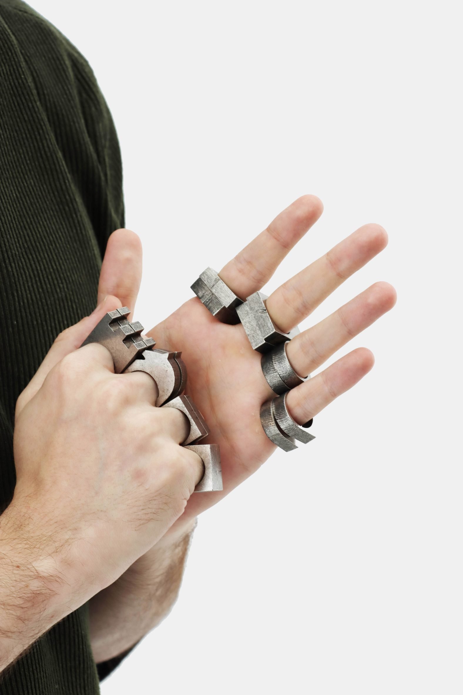 Close-up photo of a man's hands wearing chunky chess piece-shaped metal rings