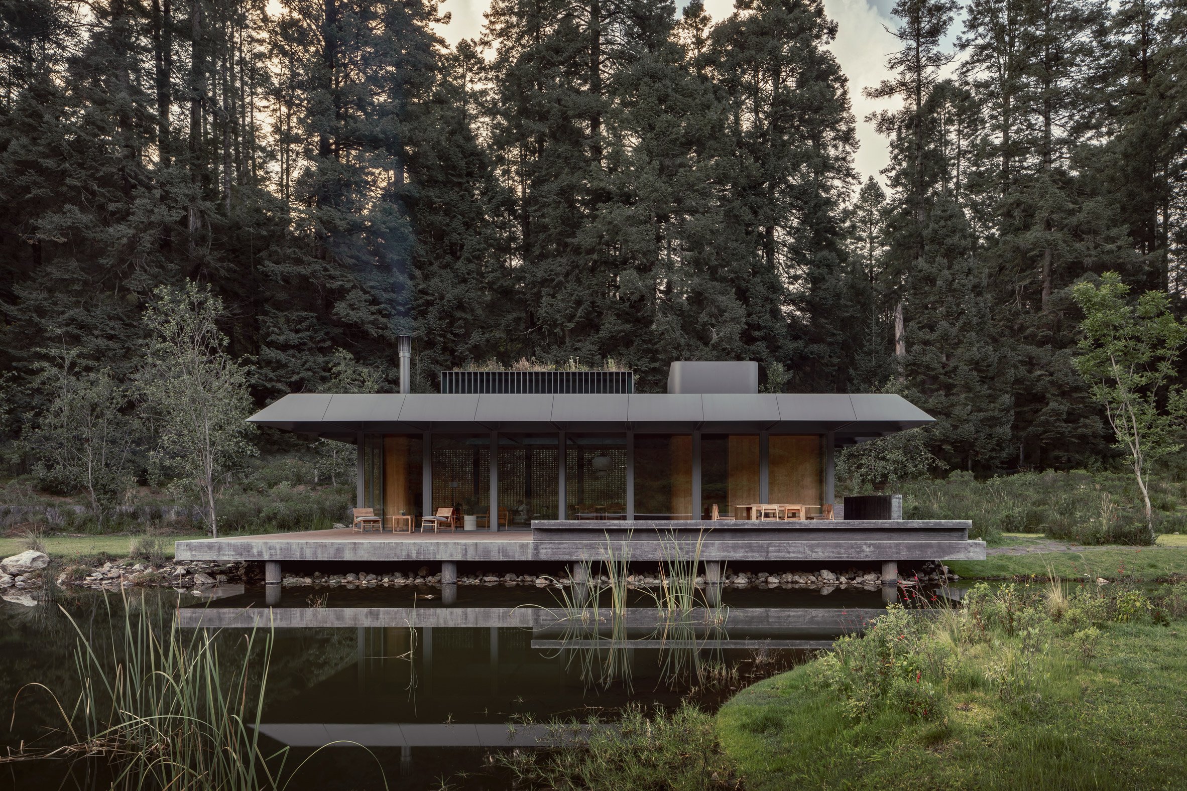 Steel house by lake with concrete foundation visible