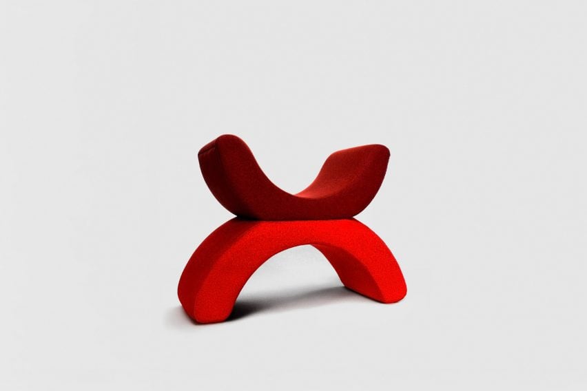 A chair with a U-shaped seat and U-shaped legs, in tones of red, photographed against a grey backdrop.